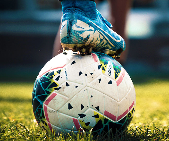 Balón de fútbol pisado por la bota de un futbolista