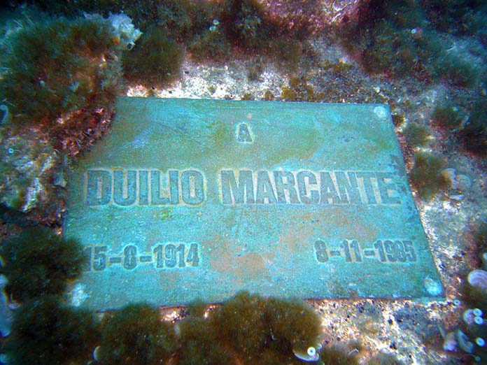 Placa conmemorativa a Duilio Marcante en la base del Cristo del abismo.