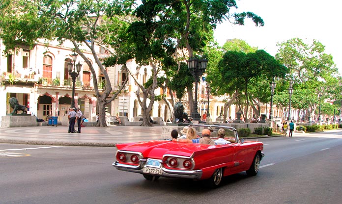 Coche descapotable recorre el Paseo del Prado con turistas a bordo