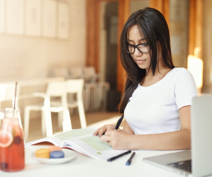 Estudiante asiática tomando apuntes con su mano izquierda