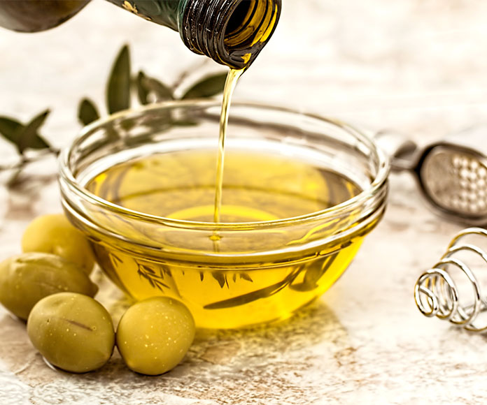 Cuenco con aceite de oliva y aceitunas alrededor