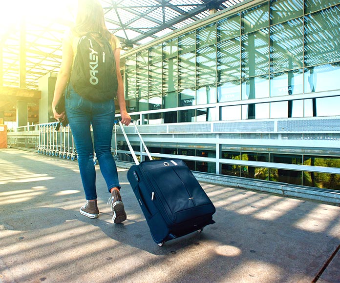 Mujer tirando de una maleta entrando a un aeropuerto