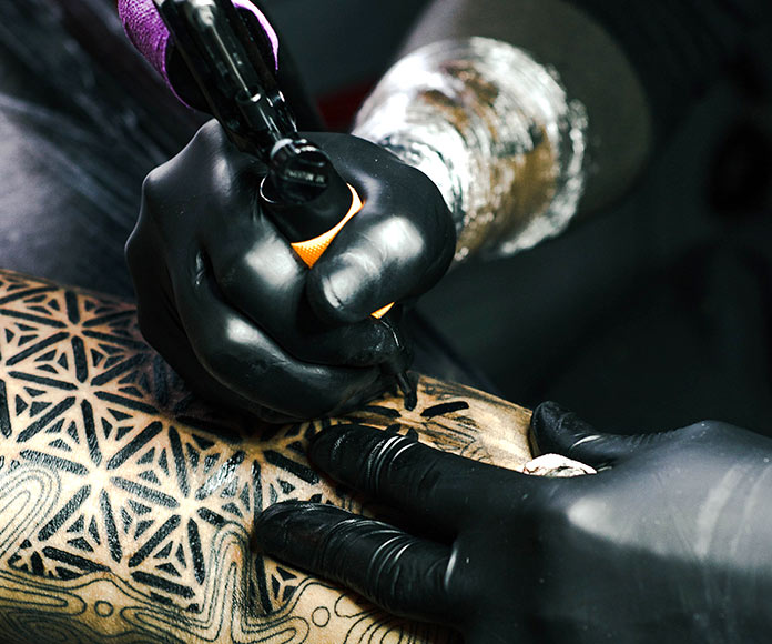 Detalle de la aguja de un tatuador haciendo un tatuaje en un brazo