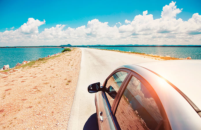 Coche circulando por una carretera al borde del mar