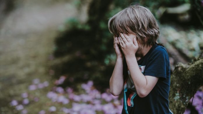 Niño tapándose el rostro