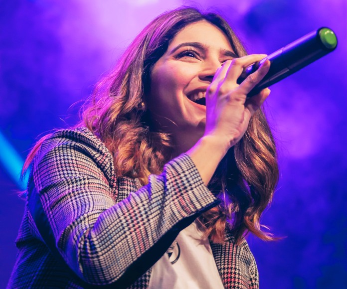 Una mujer blanca cantando sobre un escenario.