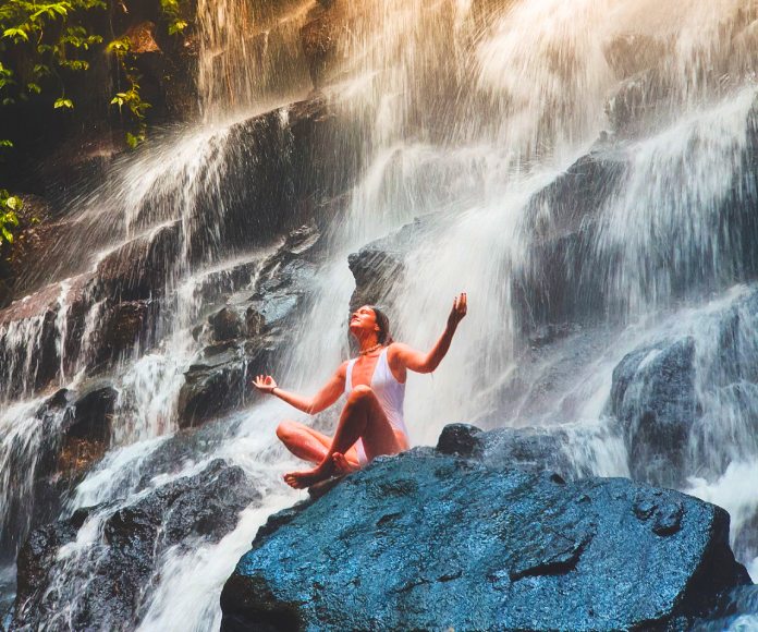 Mujer meditando bajo el río.