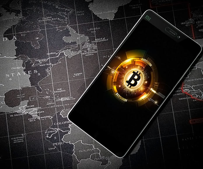 Símbolo del bitcoin en un smartphone con un mapa del mundo de fondo