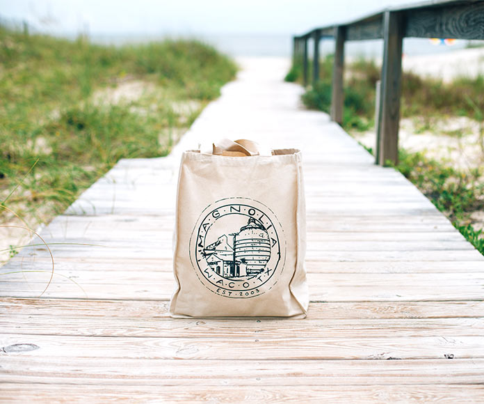 Bolso tote bag en un camino de madera hacia la playa