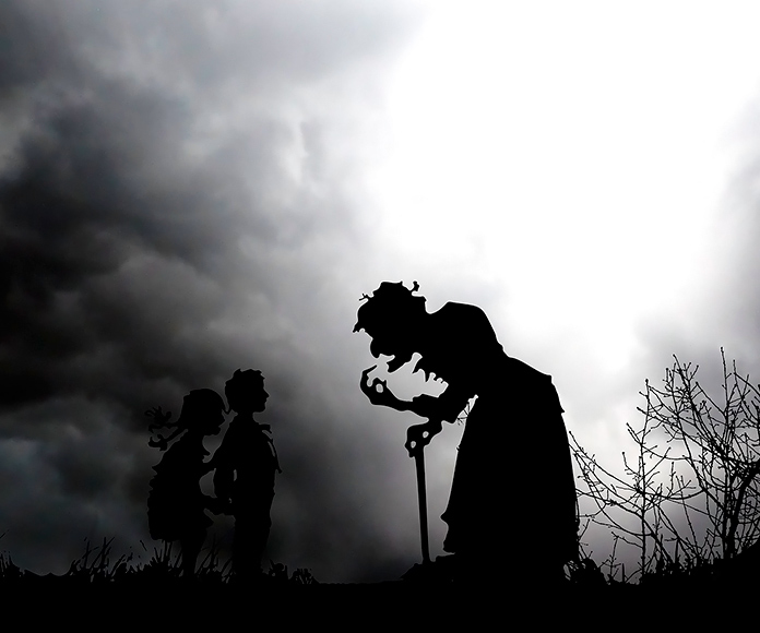 silueta de una bruja hablando con 2 niños