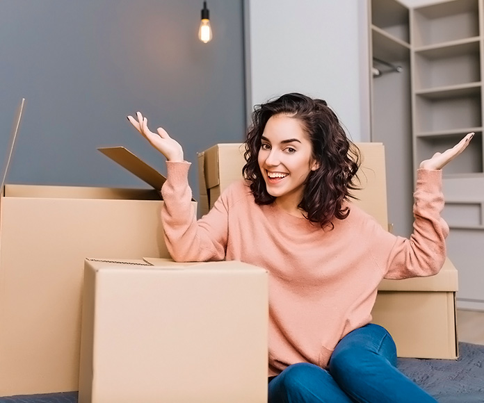 chica sonriente rodeada de cajas de cartón