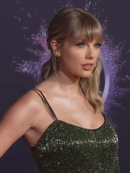 Taylor Swift luciendo un traje de brillos verdes en una alfombra roja de los MTV AMAs 2019. 