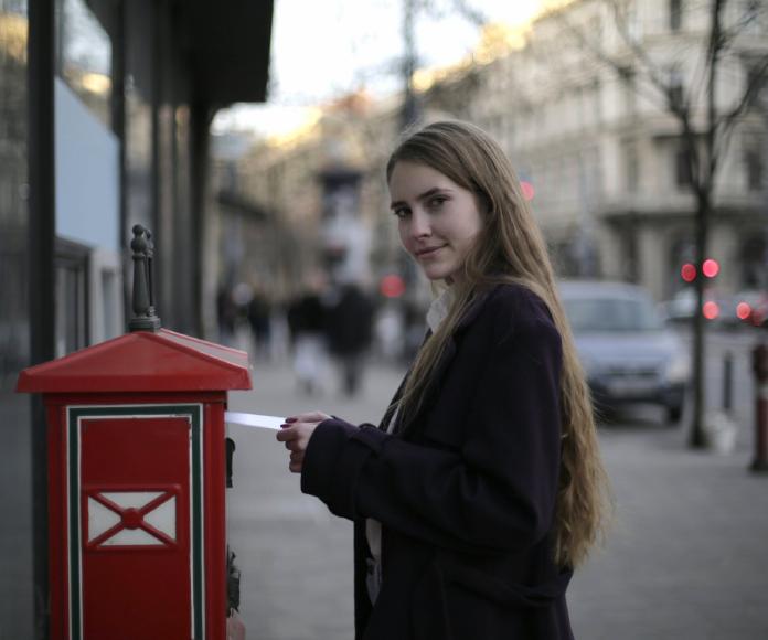 Mujer colocando carta en buzon