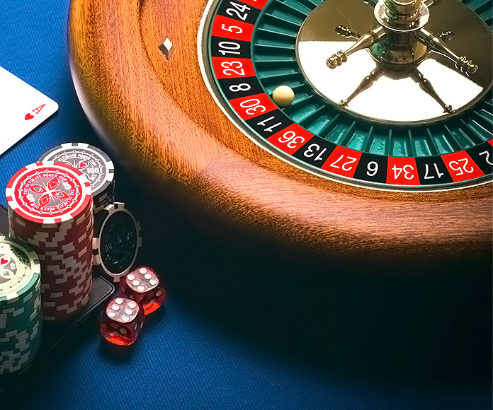 ruleta y fichas de casino junto a un ordenador portátil