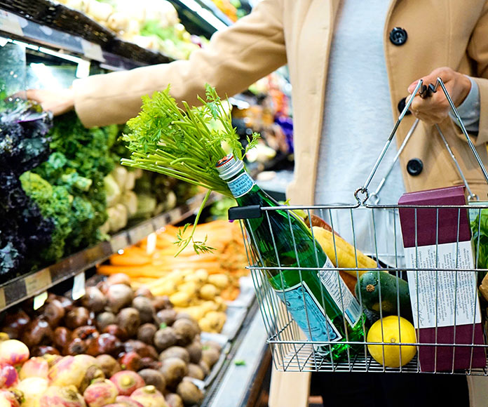Mujer con una cesta haciendo la compra de comida en un supermercado