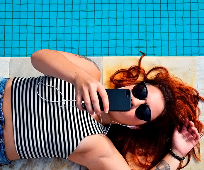 chica escuchando música en el borde de una piscina