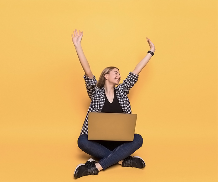 chica feliz con un ordenador portátil sobre sus piernas