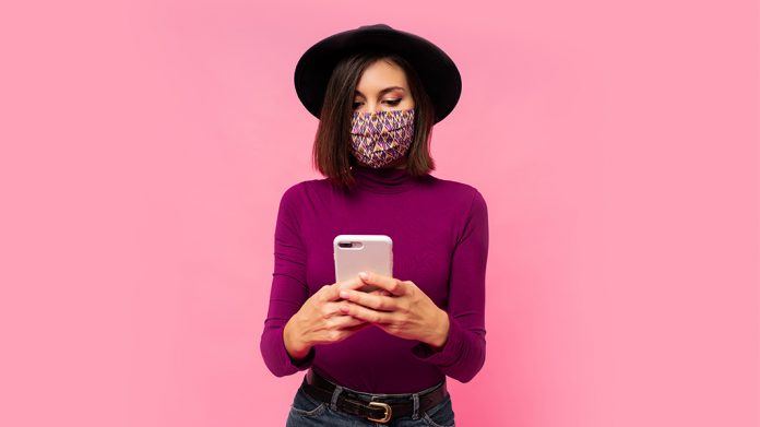 chica con mascarilla usando el teléfono móvil