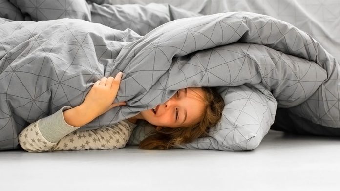 chica sonriente en la cama bajo la colcha