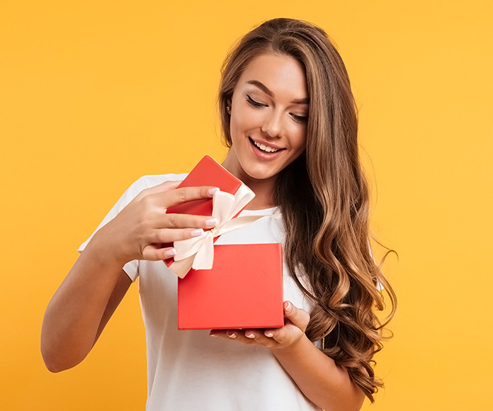 chica sonriente abriendo una caja de regalo