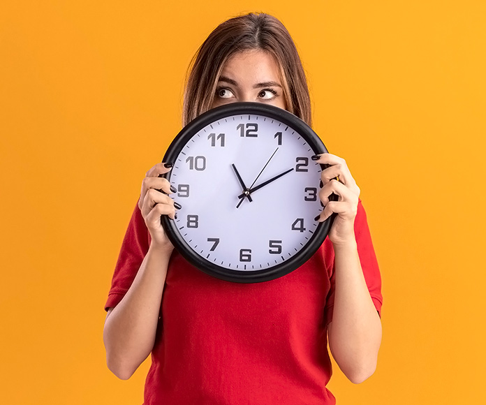 Chica sujetando un reloj de pared frente a su cara