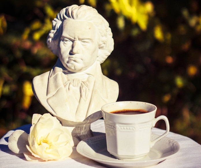 Pequeña estatuilla de Beethoven junto a una taza de café.
