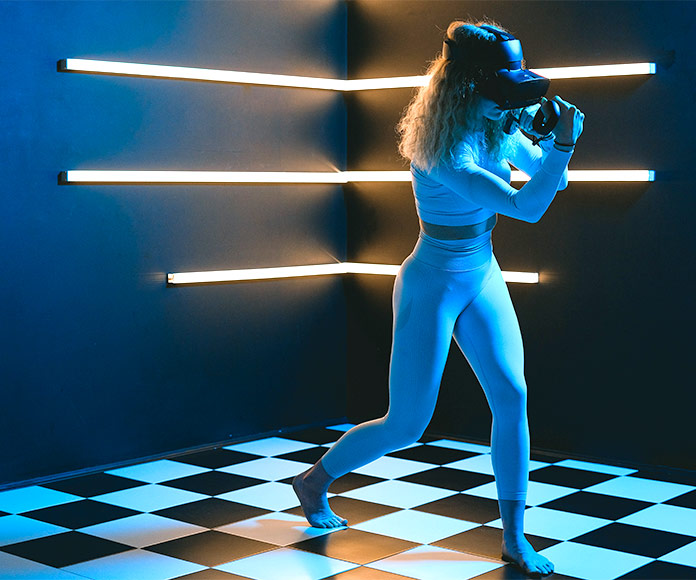 Mujer en una sala oscura jugando con gafas de realidad virtual