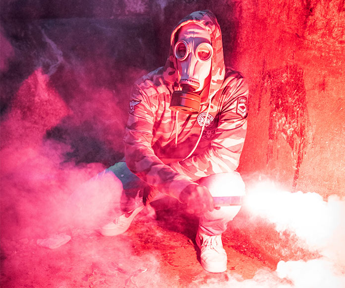 Hombre agachado con máscara anti gas y bengala roja
