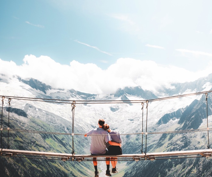 Pareja sentada en un puente sobre el vacío.