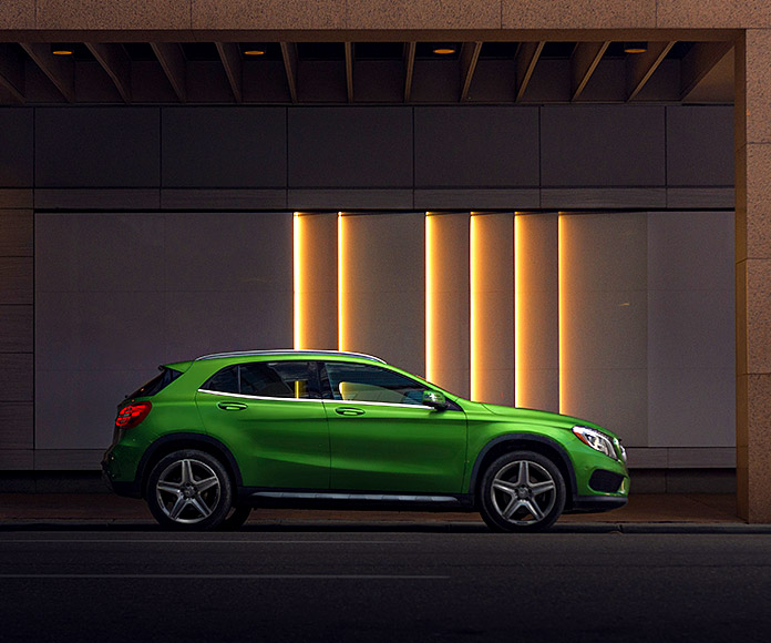 Mercedes Benz verde frente a un fondo de luces verticales
