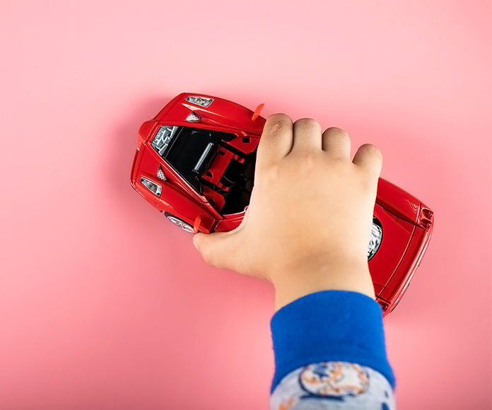 mano de niño jugando con un coche deportivo en miniatura