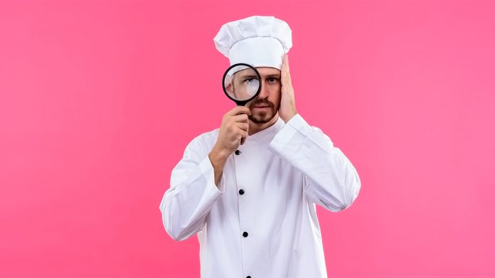 cocinero mirando a través de una lupa con cara de asombro