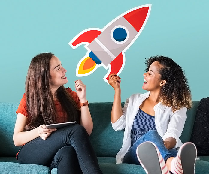 dos chicas sonrientes sujetando un dibujo de un cohete