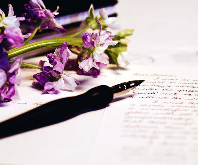 Pluma, carta y ramo de flores sobre una mesa