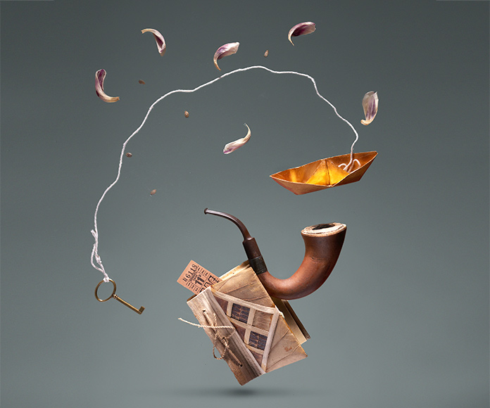 Composición ilusoria de un libro del sale una pipa, un barco de papel y una llave atada a una cuerda