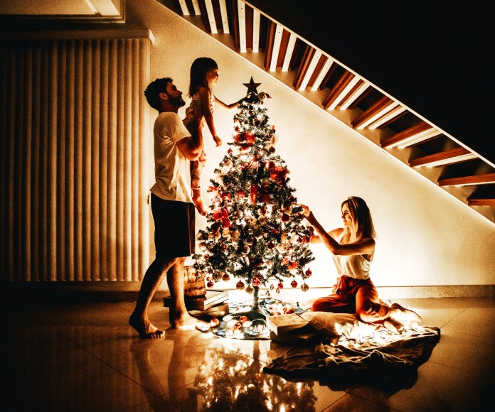 Familia decorando un árbol navideño.