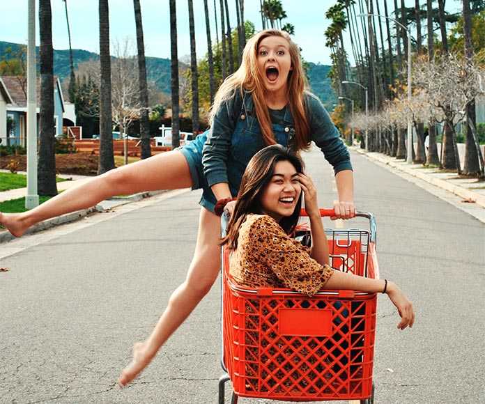 Dos chicas jugando sobre un carrito de la compra