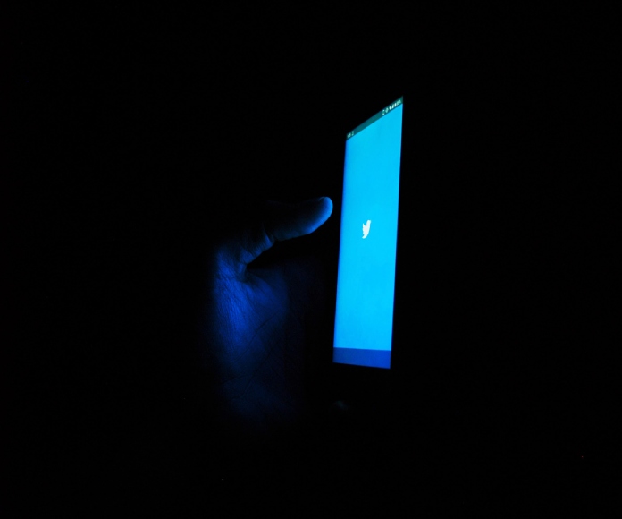 Persona usando Twitter en la oscuridad.