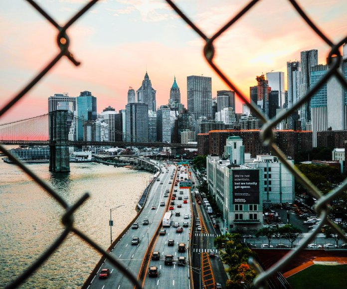 Un paisaje de ciudad visto a través de una reja rota.