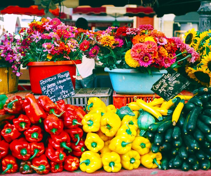 Verduras y flores apiladas en un mercado.