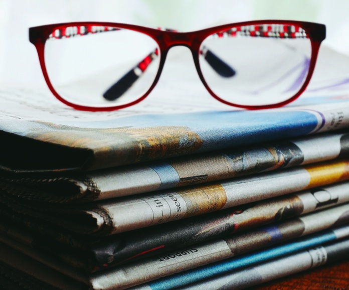 Lentes de lectura sobre una pila de diarios.