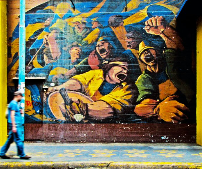 Persona caminando cerca de un mural.