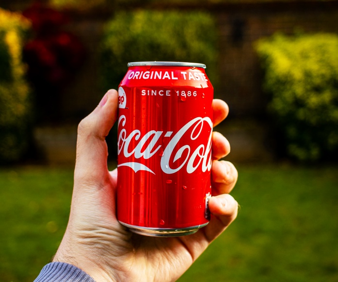 Persona sosteniendo una lata de Coca-Cola.