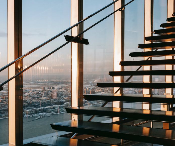 Escaleras frente a un ventanal con vistas de un edificio moderno