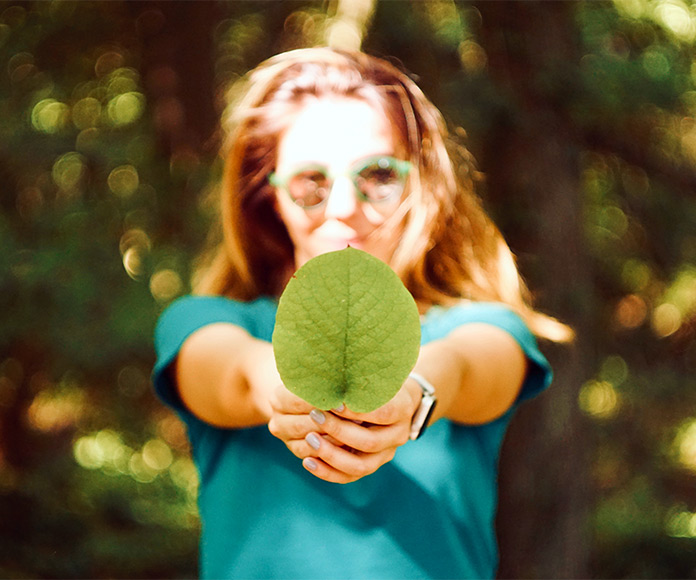 Mujer en la naturaleza mostrando una hoja