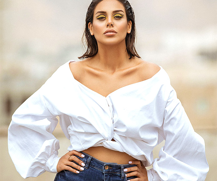 Mujer posando con camisa blanca de mangas anchas