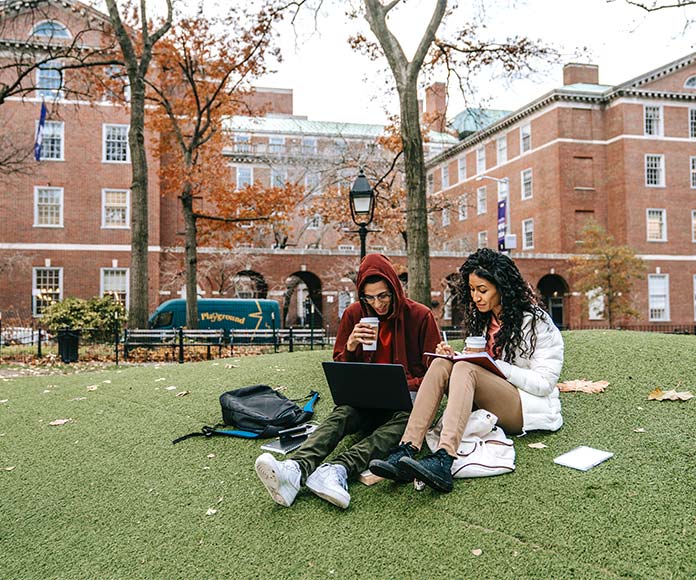 Estudiantes univesitarios sentados en el jardín de un campus