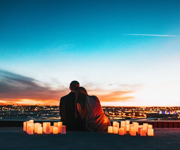 Pareja sentada sobre un techo y rodeada de velas.