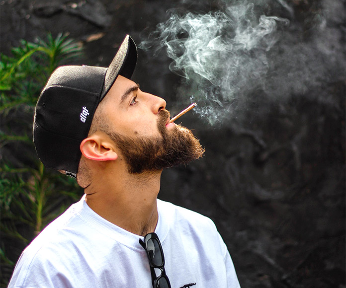 Hombre con gorra fumando de perfil