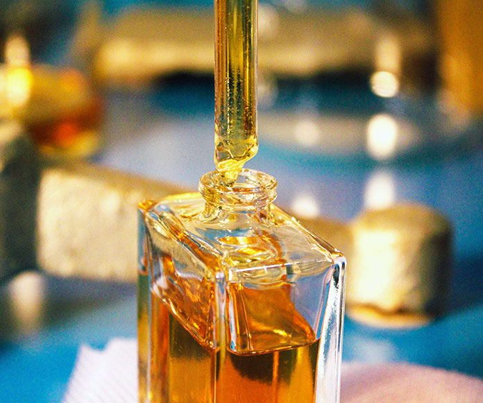 Frasco abierto con fragancia o perfume saliendo de una pipeta en un laboratorio.